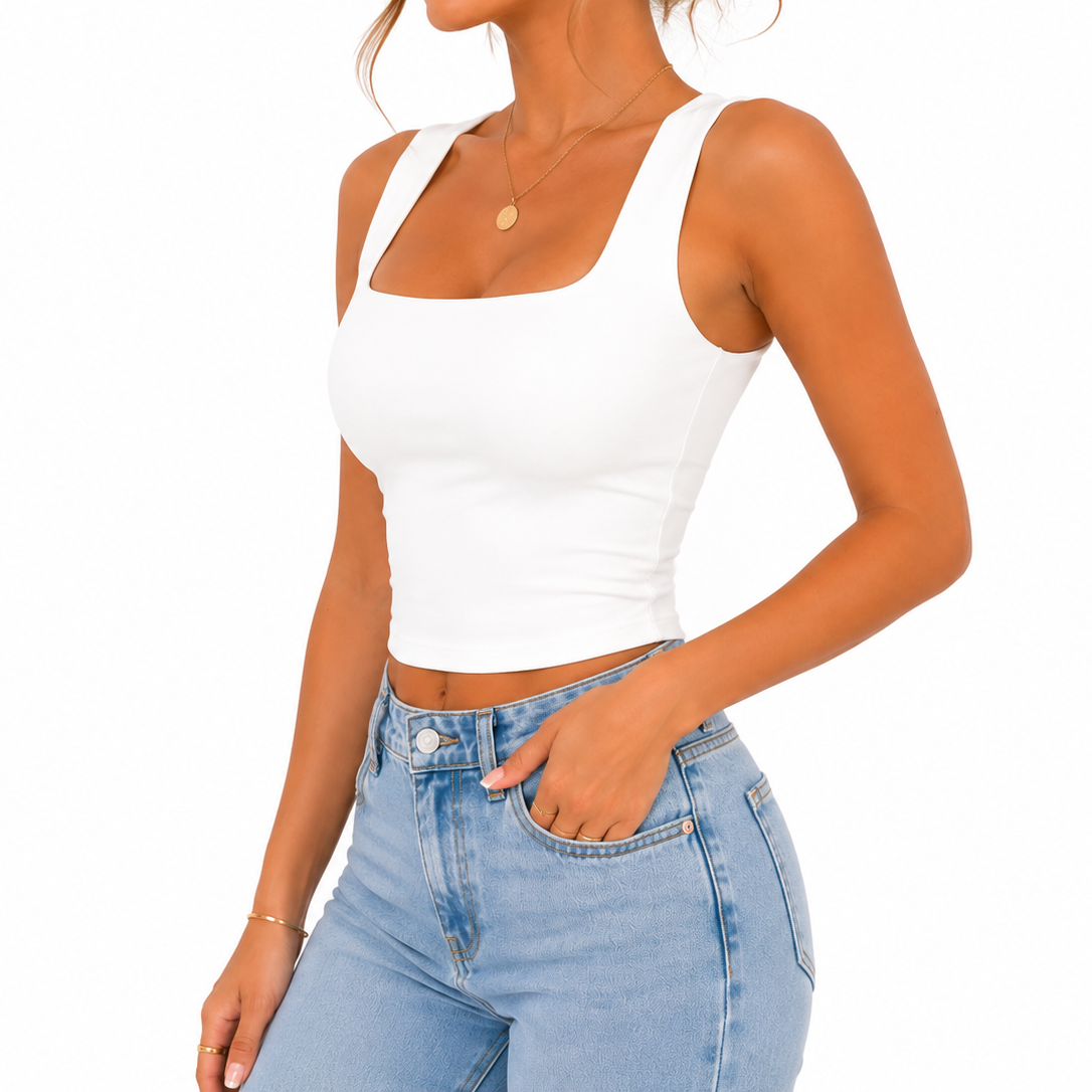 A woman wearing a fitted white scoop-neck crop tank top and light-wash blue jeans, shown from the neck down against a plain white background.